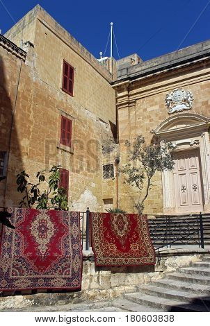 Oriental carpets hanging on a railing beside a church
