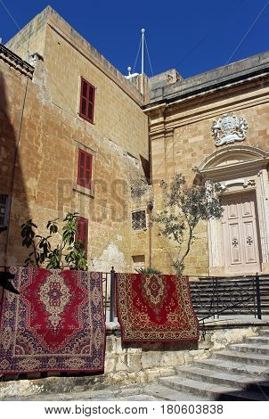 Oriental carpets hanging on a railing beside a church