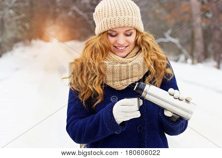 Beautiful Young Smiling Girl In Blue Jacket Pouring Tea From Thermocup. Travel Girl.