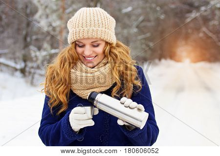 Beautiful Young Smiling Girl In Blue Jacket Pouring Tea From Thermocup. Travel Girl.