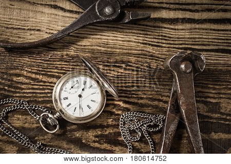 Composition with vintage pocket watch. Old rusty tools and a clock on a dark wooden background. Watch repair