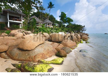 White tourist houses on берегуморя big stones. Sea surf. Green trees and sandy coast.
