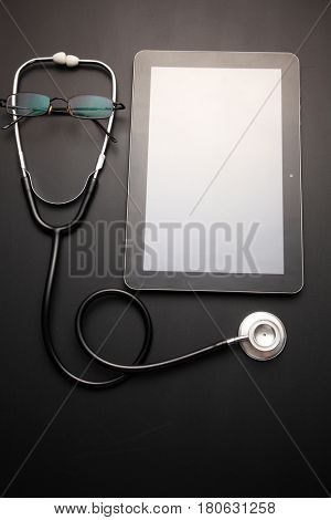 stethscope and a blank tablet on the blackboard