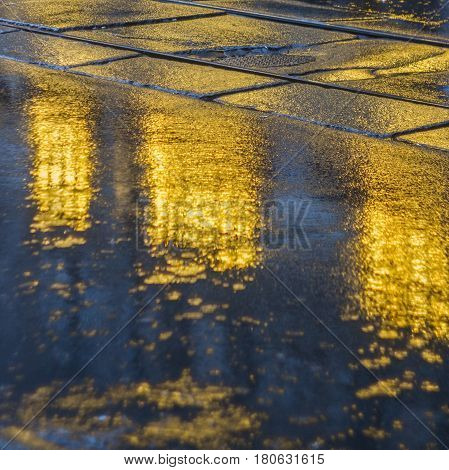 The bright lights of the evening city after rain headlights from the approaching car. View from the pavement level