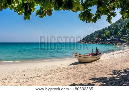 A boat at the white sand beach of the tropical blue sea. Daytime, Haad Yuan, Koh Phangan, Thailand
