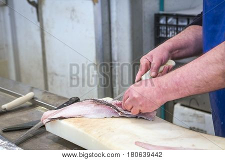 Fish seller short with a thin knife on the market of Cadiz Andalusia Spain