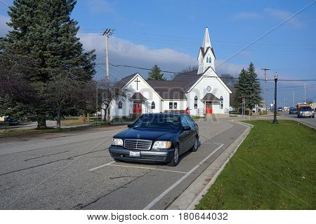 MANCELONA, MICHIGAN / UNITED STATES - NOVEMBER 27, 2016: A black Mercedes Benz S420 luxury sedan is parked in front of the Mancelona United Methodist Church in downtown Mancelona.