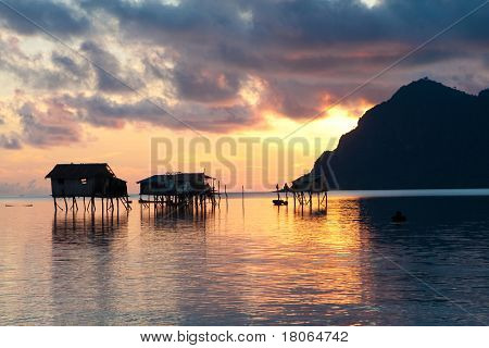 Solopgang over træ huse på pæle af øen af Maiga, Sabah, Borneo.