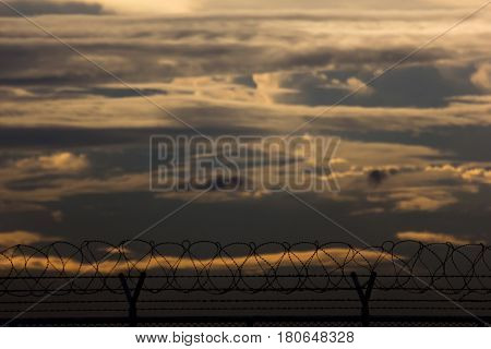 security with a barbed wire fence at sunset time