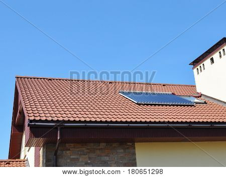 Closeup of Vacuum Solar Water Heating System Rain Gutter on the Red Tiled House Roof. Soral Energy for Energy Efficiency New House Building Concept Outdoor