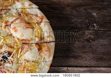 Fresh italian pizza with bacon, ham and cheese served on rustic wooden table, flat lay. Junk food, bad habits, calories. Dark background with free space for text.