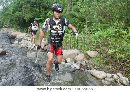SABAH, MALEISIË - 2 APRIL. Een racer uit een deelnemende team maakt hun weg langs en over een ri