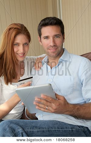 カップルの電子のタブレットでオンライン ショッピングを行う