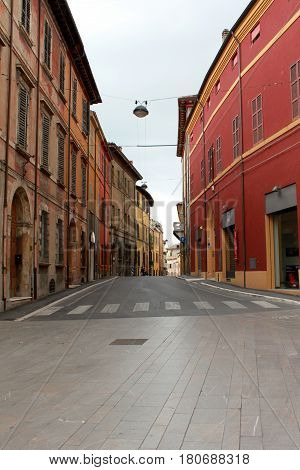 Italy. Emilia-Romagna. Cesena. Narrow street with red buildings on blue sky background. Vertical view