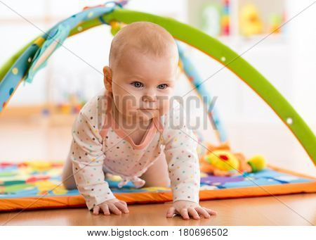 Closeup of happy seven months baby crawling on colorful playmat
