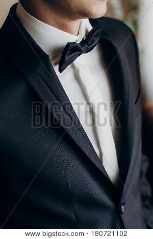 Stylish Groom With Bow Tie Getting Ready In The Morning In Hotel Room. Preparation For Wedding Cerem