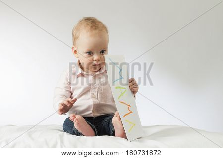 Thougtful baby holding nameplate in his hands. Horizontal studio shot. Idea for postcards. Copy space. Mothers day.