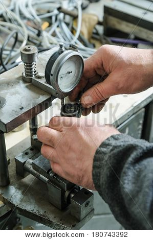Mechanics a repairing a diesel injector. Worker's hands holds the injector. A man measures the depreciation of the nozzle.