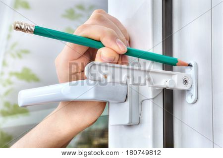 Close-up marking of holes for fastening the stopper to the PVC window.