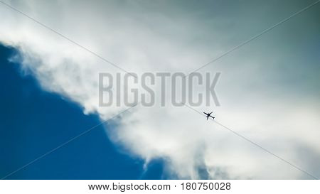 Silhouette of an airplane in clouds against a blue sky.