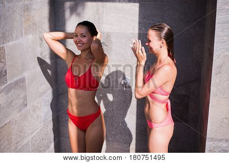 Shower On Beach. Two Beautiful Fit Woman Taking Shower At Swimming Pool. Girls With Sexy Body In Swimsuit Showering Under Water, Washing Hair, Cleaning Body And Skin Outdoors At Luxury Spa Resort In Summer.