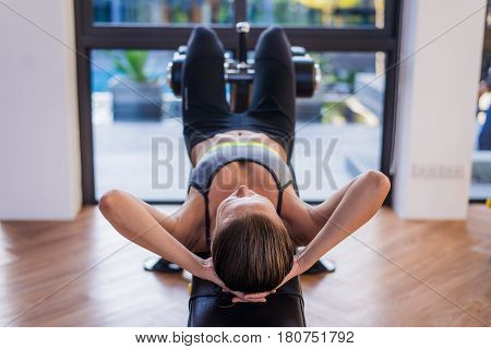 portrait of an athletic woman doing exercising abdominals work-out lying in gym at luxury hotel at summer.