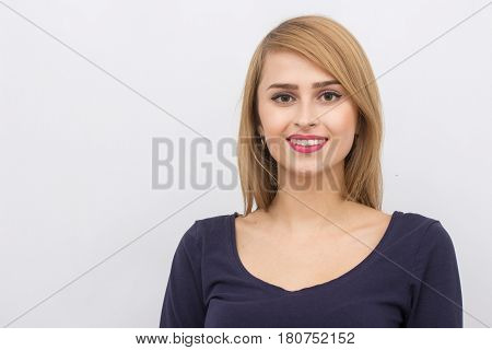 Fashion portrait of a girl posing in bright, spacious studio with a gray background in a stylish comfortable and simple clothes. young girl with clean skin and perfect face
