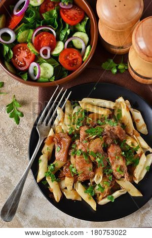 Homemade penne pasta with sauce and chicken for dinner on a concrete background