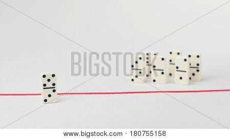 Expelled from the group, unable to cross the red line that separates them. Scene with group of domino. Concept of accusation guilty person, bulling or outcast in the team. Bright background.