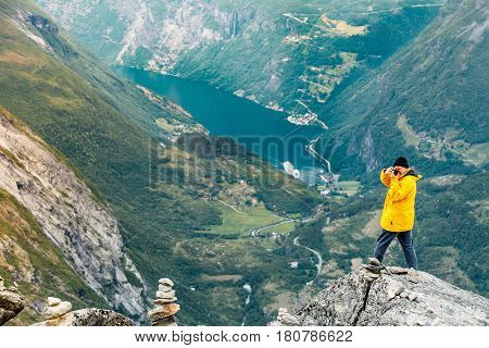 Tourism vacation and travel. Male tourist taking photo with camera enjoying Geiranger fjord and mountains landscape from Dalsnibba Plateau viewpoint Norway Scandinavia.