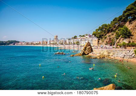 panoramic view of seashore with rock cliff and a town on background in Lloret de Mar, Catalonia, Costa Brava, Spain