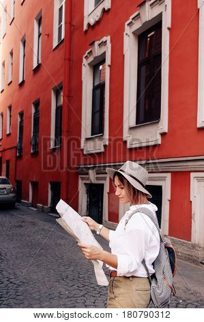 Travel guide. Young female traveler with backpack and with map on the street. Travel concept. Adventure