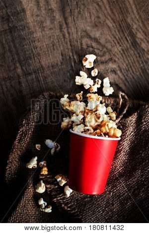 Fresh Popcorn in a red cardboard box on the wooden table Cinema concept