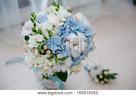 Delicate and tender marriage bouquet in white and light blue colours with bow and ribbons