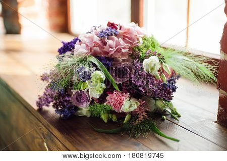 Tenderless bouquet with bow and ribbons in green and pink and blue colours on brown background