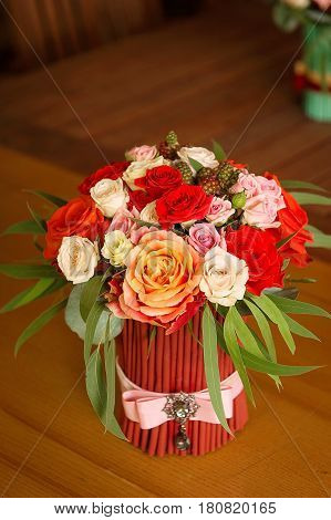 Tenderless bouquet with bow and ribbons in gaudy red and orange colours, staying on brown background