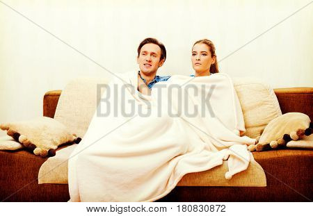 Smiling loving couple sitting on couch with blanket