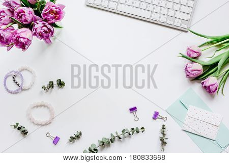 Spring pink flowers on workdesk at home ofiice white background top view mockup