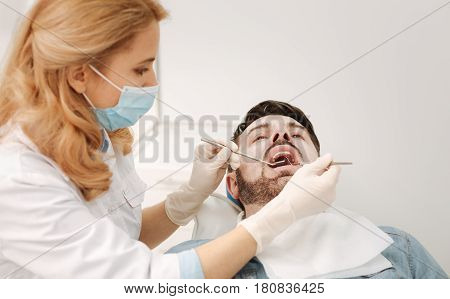 Architect of a smile. Scrupulous prominent nice specialist using sterile equipment while working on her patients healthy smile