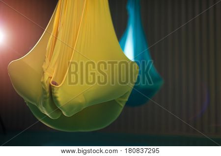 Unrecognized people practicing aerial yoga meditation. Group of adults doing exercises in hammocks. Body balance and antigravity training. Wellness and bodycare concept