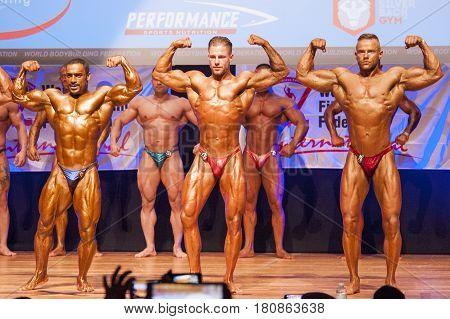 MAASTRICHT THE NETHERLANDS - OCTOBER 25 2015: Male bodybuilders flex their muscles and shows their best front double biceps pose on stage at the World Grandprix Bodybuilding and Fitness of the WBBF-WFF