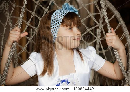 Little girl is sitting on a chair close-up