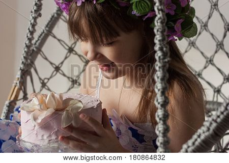 Little girl in a beautiful dress with flowers and a cake