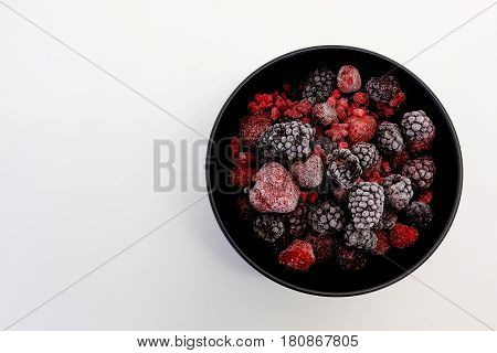Frozen Berries in black bowl on white surface