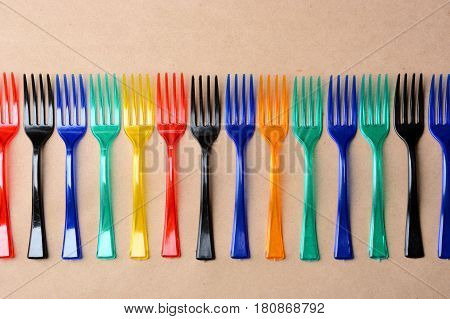 many color plastic forks on paper background