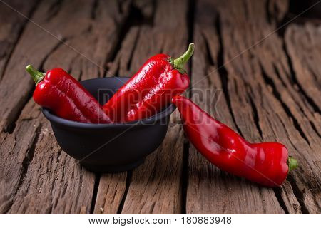Red chilly pepper on wooden black background. Red hot chili peppers. Domestic cultivation extra hot chilli burn.