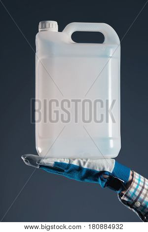 Unrecognizable male farmer with unlabeled plastic tank canister containing pesticides for plant processing in agriculture