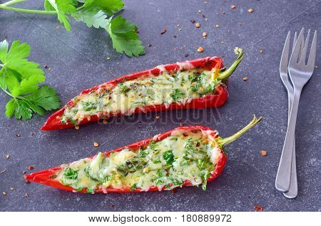 Oven cooked red paprika stuffed with cheese garlic and herbs on an abstract grey background. healthy eating concept. Mediterranean lifestyle.