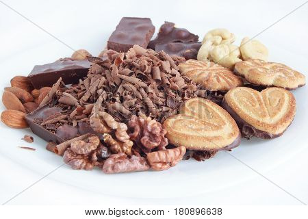 Chocolatecookies and nuts lying at the white plate. Isolated objects.
