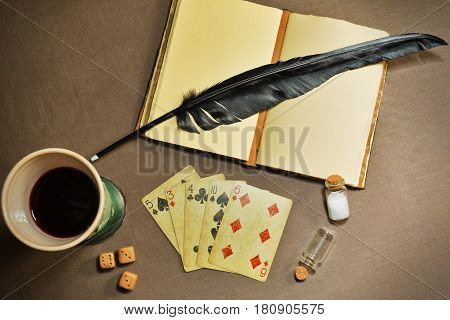MOSCOW, RUSSIA - APRIL 10, 2017: Poker cards, quill, noebook and a glass of wine on the textile cloth